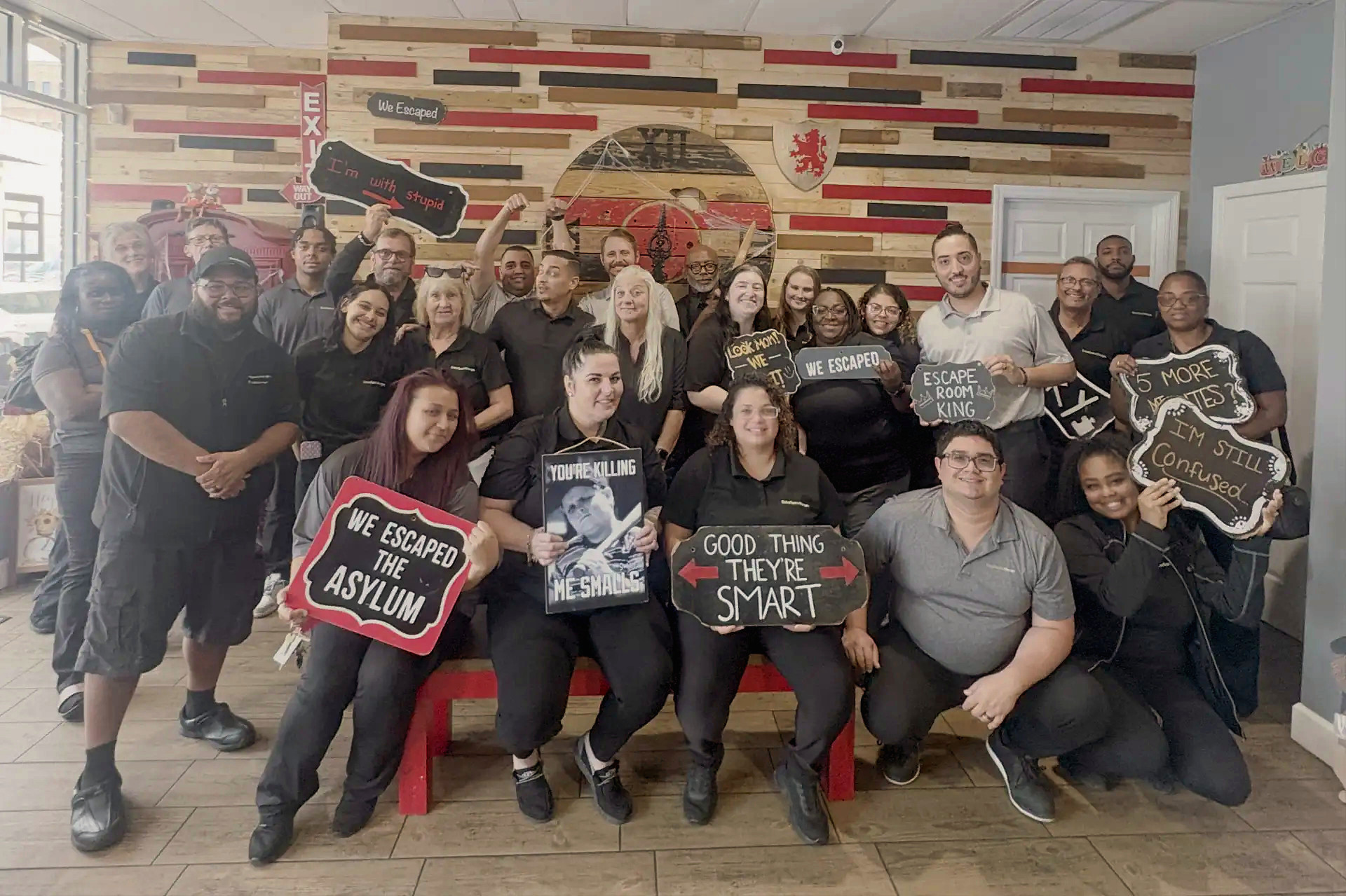 Kristian's team of 26 coworkers smiling and holding funny signs after their downtown Lakeland team event.